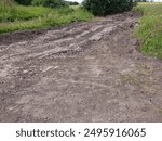 A dirt road dug by an excavator. Field road with big holes dug in the field. The topic of bad roads.