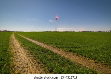 Dirt Road In The Field Leading To The Wind Turbines.