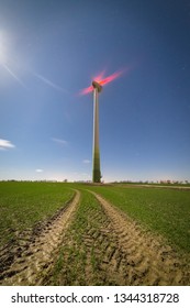 Dirt Road In The Field Leading To The Wind Turbines.