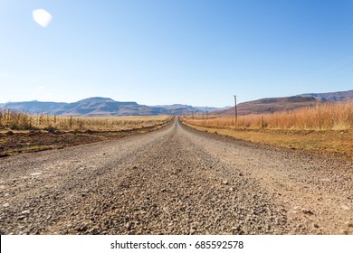 dirt road leading nowhere, mountain background, lens flare