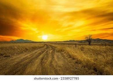 A dirt road leading off into the sunset with dramatically colored skies. - Shutterstock ID 2338927785