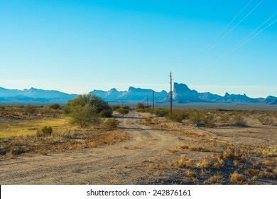 A Dirt Road Lined With Telephone Poles On One Side