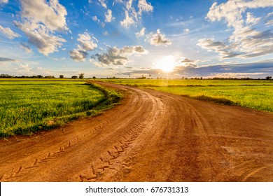 Dirt road in the rice field at sunset, countryside of Thailand