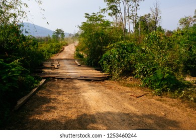 Dirt Road With Rickety Wooden Bridge In Rural Asia