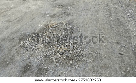 a dirt road surface with a significant structural failure known as a pothole or crater. Such conditions make commuting difficult and risky for both pedestrians and vehicles