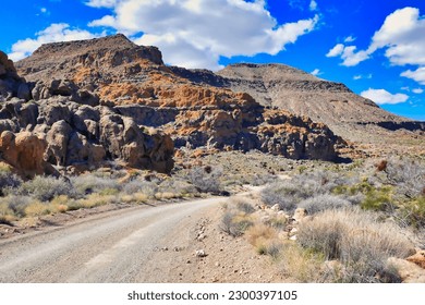 Dirt road through the eroded volcanic rock landscape in the Providence Mountains, close to Hole-in-the-Wall, Mojave National Preserve, California, USA
				