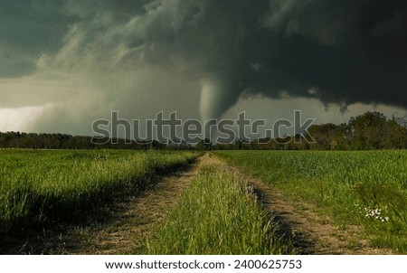 Dirt road through the field with a thunderstorm in the background