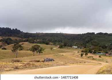 A Dirt Road Winding It's Way Through The Rolling Hills Of Drought-stricken Australian Dairy Farm On Top Of A Mountain Range