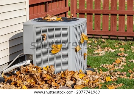 Dirty air conditioning unit covered in leaves during autumn. Home air conditioning, HVAC, repair, service, fall cleaning and maintenance concept.