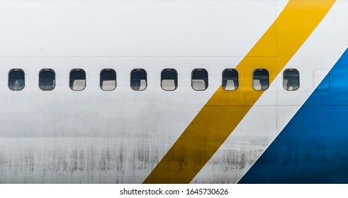 Dirty aircraft body with windows. Yellow and blue lines. Airplane details.