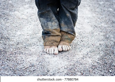 Dirty And Bare Child's Feet On Gravel. Poverty Concept