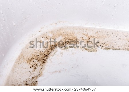 Dirty bathtub surface with a metal drain hole.