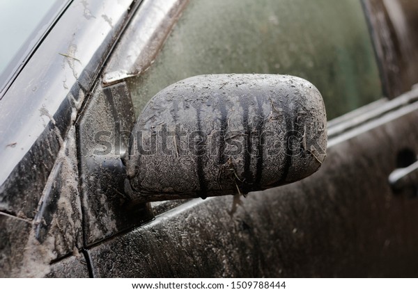 Dirty black\
car. Very dirty car mirror. Close\
up.