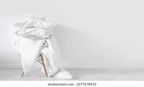 dirty blanket, linen bedding, cotton sheets, cushions and duvet with natural material on chair on white wall background with copy space, washing concept  - Shutterstock ID 2277678923
