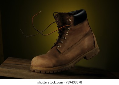 Dirty boot isolated over dark yellow background - Shutterstock ID 739438378