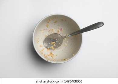 Dirty Bowl With Food Leftovers And Spoon On White Background, Top View