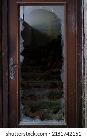 dirty broken door frame with hole in center, sharp pieces of glass sticking out, concept shot, military operations, destruction of buildings from bombing and rocket attacks, blast wave