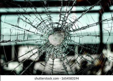 Dirty, Broken Safety Glass Window. Laminated Glass Layers Shattered In A Spiderweb Pattern, With The Plastic Safety Layer Visible In The Center, Holding The Pieces Together. Abstract Background