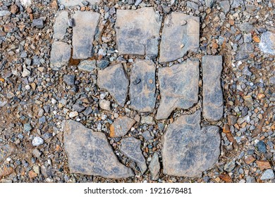 A Dirty Broken Stone Tile On Gravel. The Tile Is Arranged To It Is Obvious How It Fit Together Before It Was Broken. Some Bits Missing.