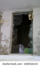 dirty broken window frame with hole in center, sharp pieces of glass sticking out, concept shot, military operations, destruction of buildings from bombing and rocket attacks, blast wave