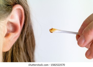 Dirty Brown Ear Wax Cotton Swab Stick Held Between Fingers By Young Caucasian Woman Close To Ear Isolated Against White Background No Face Or Eyes 2020