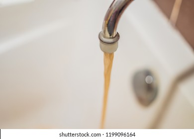 Dirty Brown Running Water Falling Into A White Sink From Tap. Environmental Pollution Concept.