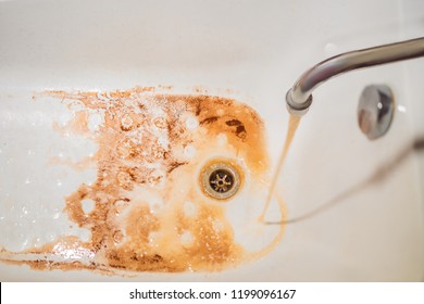 Dirty Brown Running Water Falling Into A White Sink From Tap. Environmental Pollution Concept.