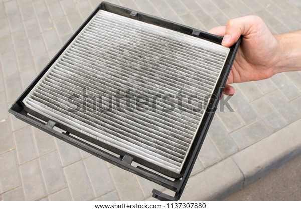 Dirty cabin\
air conditioner filter for car, man holds in his hand. Need to\
replace the old used. Background in\
blur.