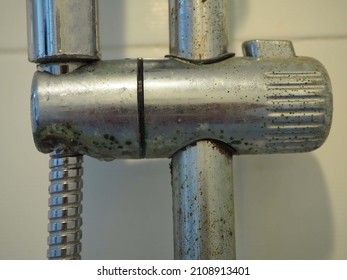 Dirty calcified shower mixer tap and shower hose, faucet with limescale or lime scale on it, close up photo, blurred.
