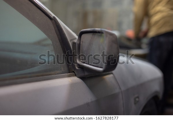 Dirty car in the\
dust, distant view\
mirror.