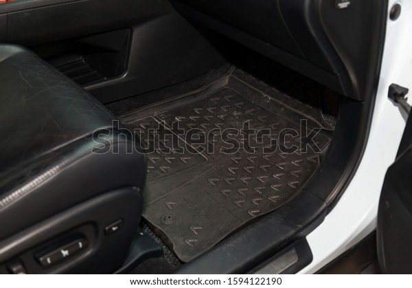 Dirty car floor mats of\
black rubber under passenger seat in the workshop for the detailing\
vehicle before dry cleaning. Auto service industry. Interior of\
sedan.