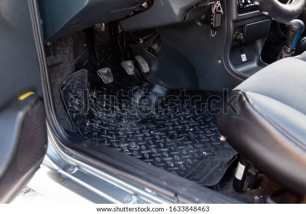 Dirty car floor mats\
of black rubber with gas pedals and brakes in the workshop for the\
detailing vehicle before dry cleaning. Auto service industry.\
Interior of sedan.