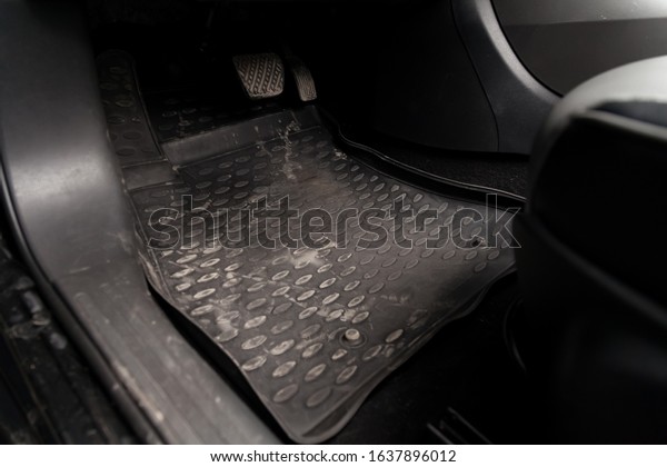 Dirty car floor mats of black rubber with gas\
pedals and brakes in the workshop for the detailing vehicle before\
dry cleaning