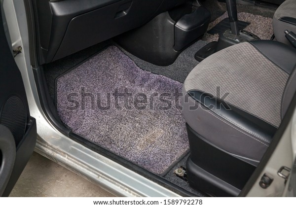 Dirty car floor mats of gray\
carpet under passenger seat in the workshop for the detailing\
vehicle before dry cleaning. Auto service industry. Interior of\
sedan.