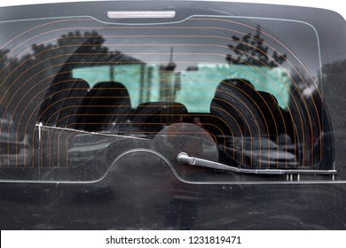dirty car glass in a layer of dust wiped by a wiper, close up of the rear window of the heated black car.