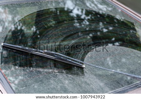Dirty car window with a wiper blade