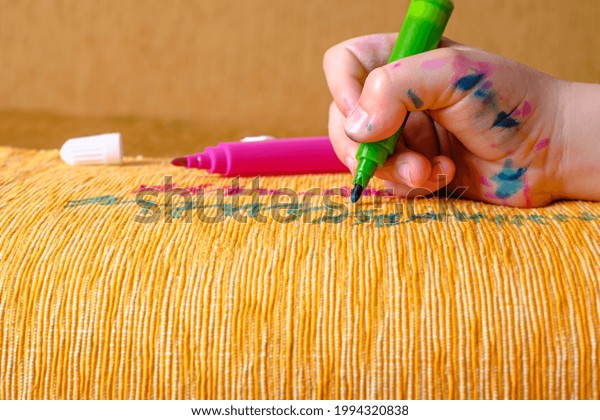 Dirty children\'s hand in colored\
markers draws with a green felt-tip pen of the couch. daily life\
dirty stain for wash and clean concept. High quality\
photo