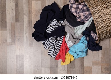 Dirty Clothes Scattered From Laundry Basket On Floor, Top View. Space For Text