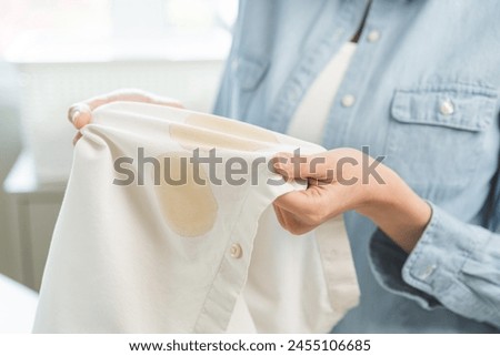 Dirty coffee stain cloth, housewife asian young woman holding white shirt, showing making cloth stain, spot dirty or smudge on clothes for cleaning before washing, maid female working at home concept