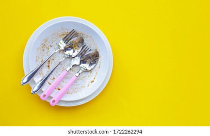 Dirty Dishes With Spoon And Fork On Yellow Background. Top View