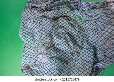 Dirty And Faded Torn Dish Cloth Isolated On A Dark Green Background 