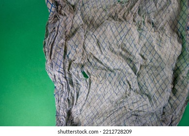 Dirty And Faded Torn Dish Cloth Isolated On A Dark Green Background