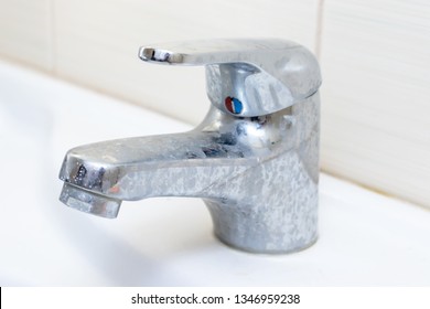 Dirty faucet with limescale, calcified water tap with lime scale on washbowl in bathroom.
