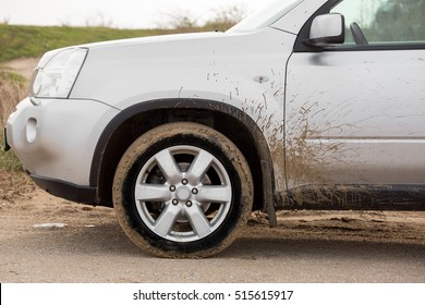 Dirty Front Wheel Of The Off-road Car With Swamp Splashes On A Side Panel And A Front Driver's Door.