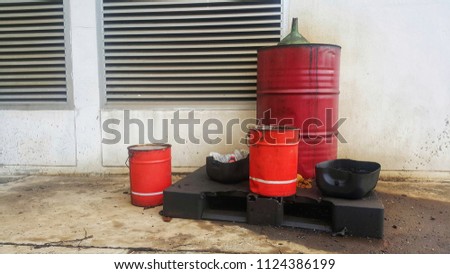 Dirty greasy barrels outside building with grease barrels.Disposed used  oil on cover of barrel and spillage on floor