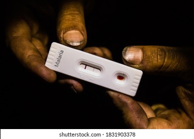 Dirty Hands Holding A Positive Malaria Test In The Dark