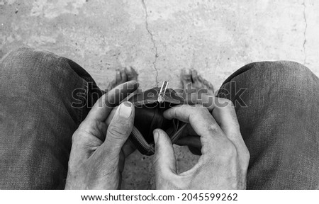 The dirty hands of a homeless poor man with an empty wallet. An unemployed man. Bankruptcy of the enterprise. Poverty and misery. Citizens in need. Hunger and cold. Bare feet without focus.