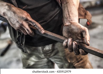Dirty hands of mechanic holding hex metal stick