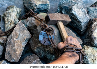 The dirty hands of a slave hold a hammer among the stones. Slave hard labor in the quarries. The symbol of slave labor.