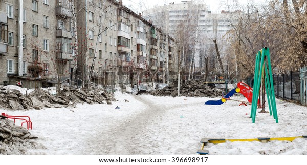 Dirty heaps of snow in the yard of an\
apartment building in\
Novosibirsk.
